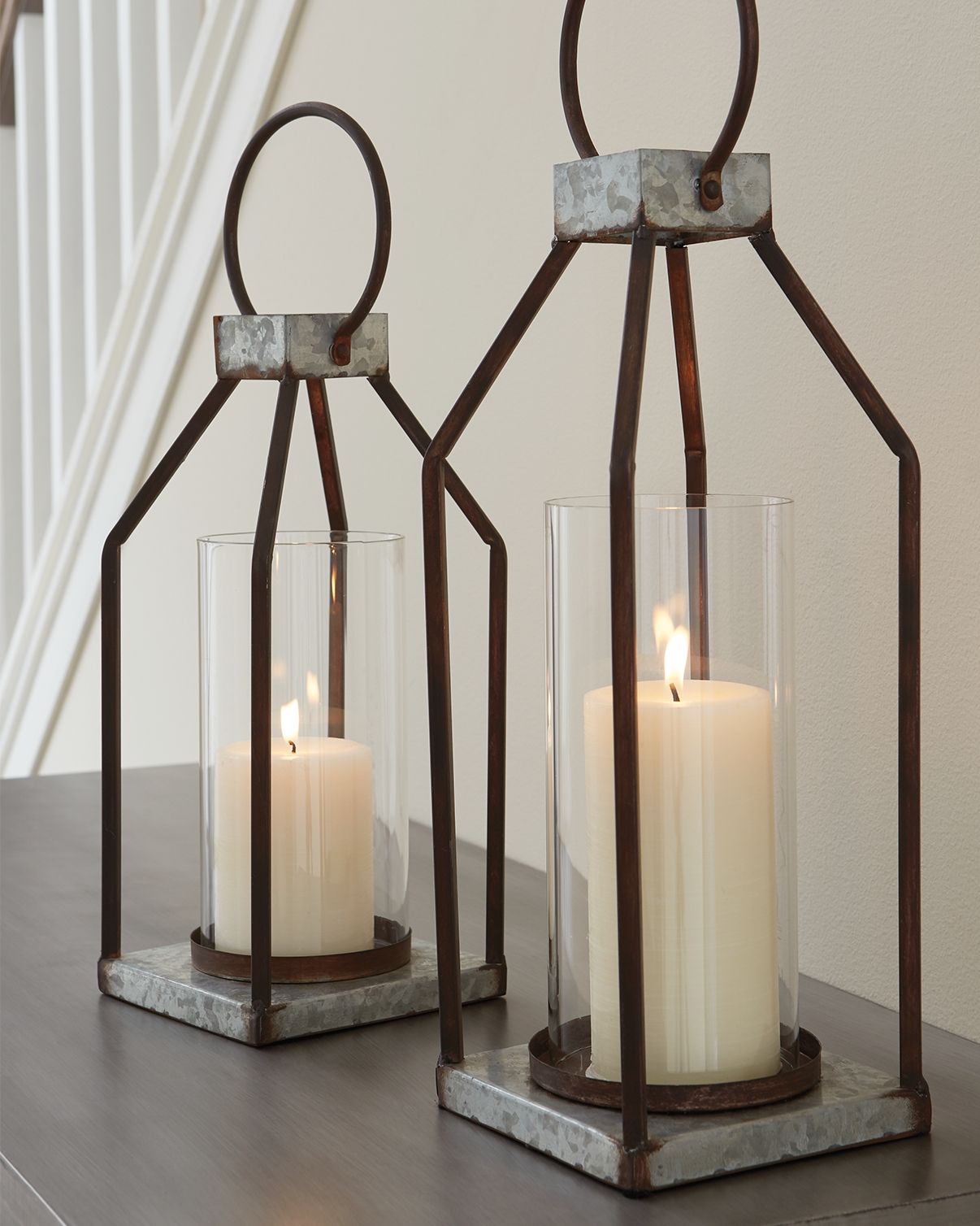 Gray/black metal lanterns with clear glass cylinders and lit candles, square stone bases (2)