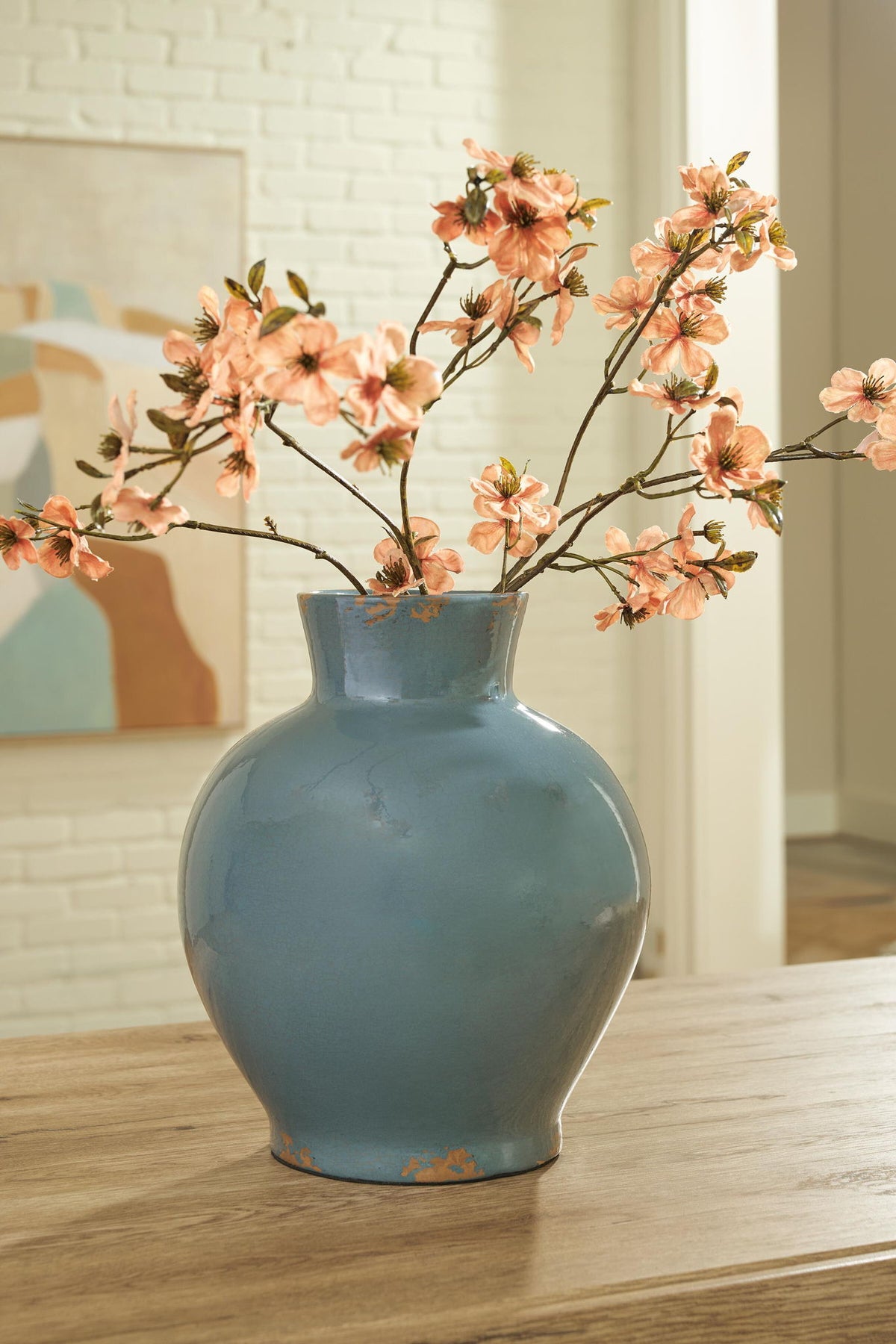 Blue ceramic vase with orange flowers and glossy glaze, featuring a distressed speckle pattern