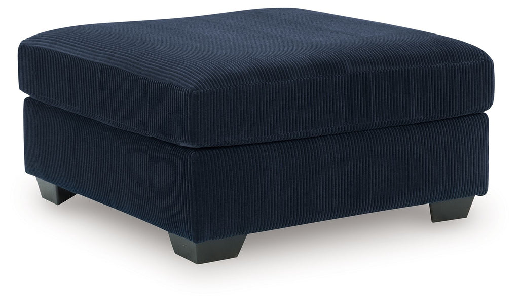 Navy oversized ottoman with ribbed fabric, square padded top, dark legs.