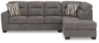 Dark gray sectional sofa with right chaise, tufted cushions, and two striped accent pillows