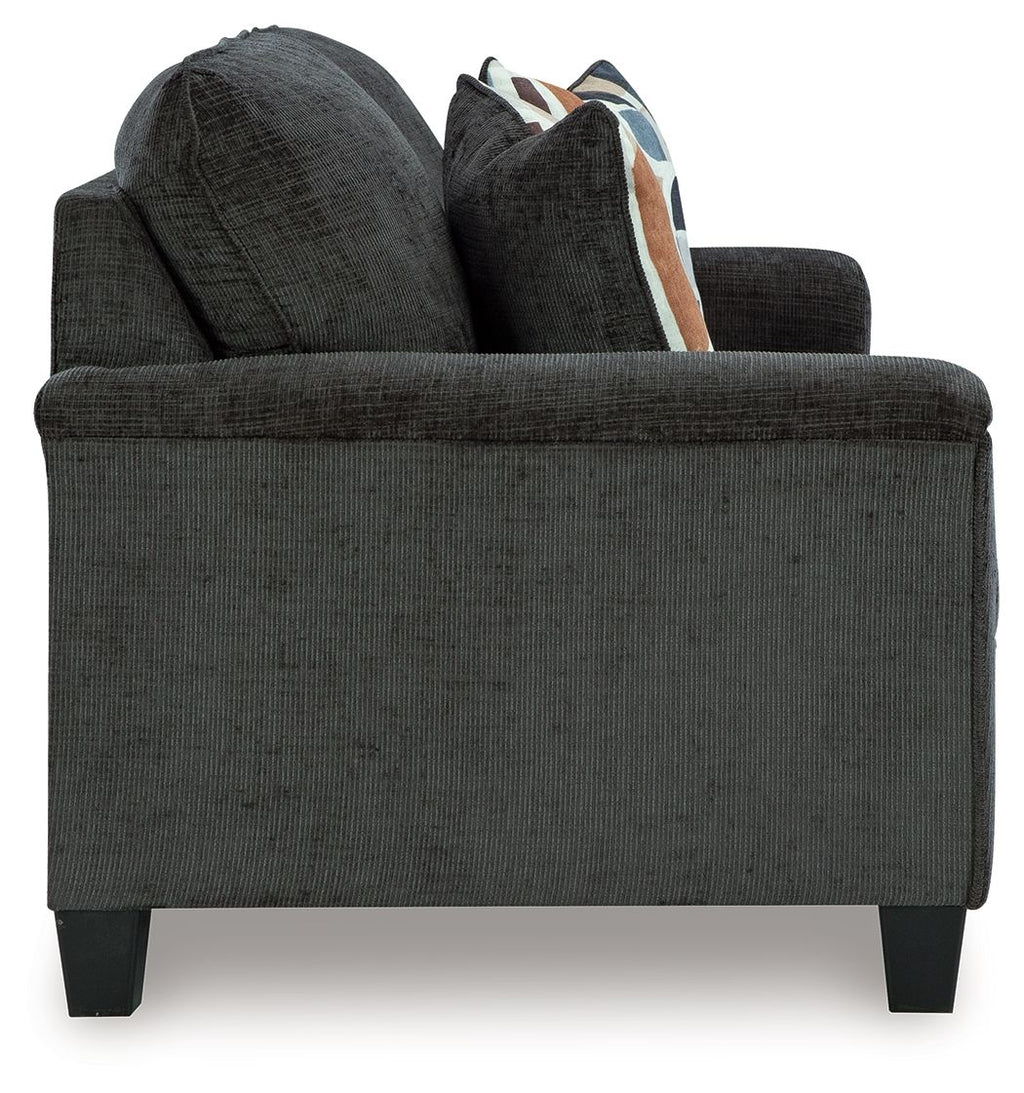 Dark gray sofa arm and seat with loose cushions and patterned pillow