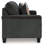 Dark gray sofa arm and seat with loose cushions and patterned pillow