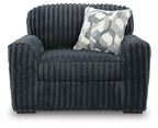 Dark gray chair and a half with quilted seat and geometric throw pillow