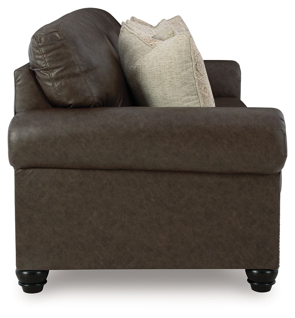 Dark brown upholstered sofa section with tall back and two beige accent pillows.