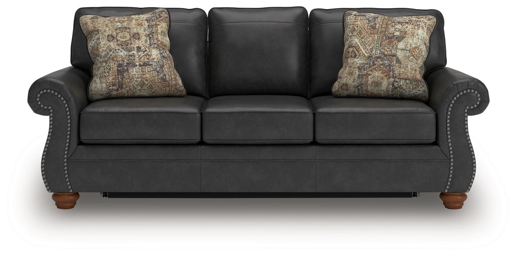 Dark gray sofa sleeper with round arm detailing and two patterned throw pillows