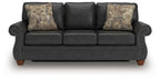 Dark gray sofa sleeper with round arm detailing and two patterned throw pillows