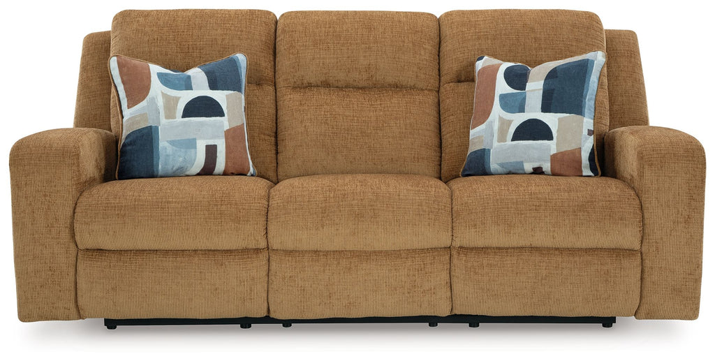 Honey reclining sofa with two patterned throw pillows, front view