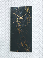 Wall clock with black hands and dark gold-veined marble design on vertical panel