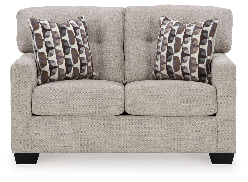 Light beige loveseat with two patterned throw pillows and split seat cushions