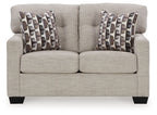 Light beige loveseat with two patterned throw pillows and split seat cushions