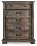 Light brown five-drawer chest with black metal knobs and decorative top panel molding