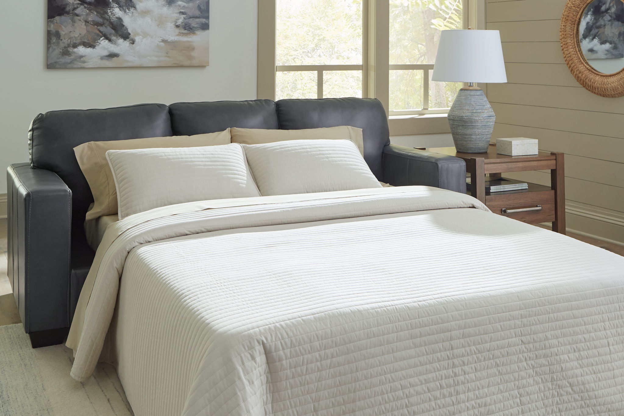 Sofa sleeper opened into a bed with white mattress and two pillows