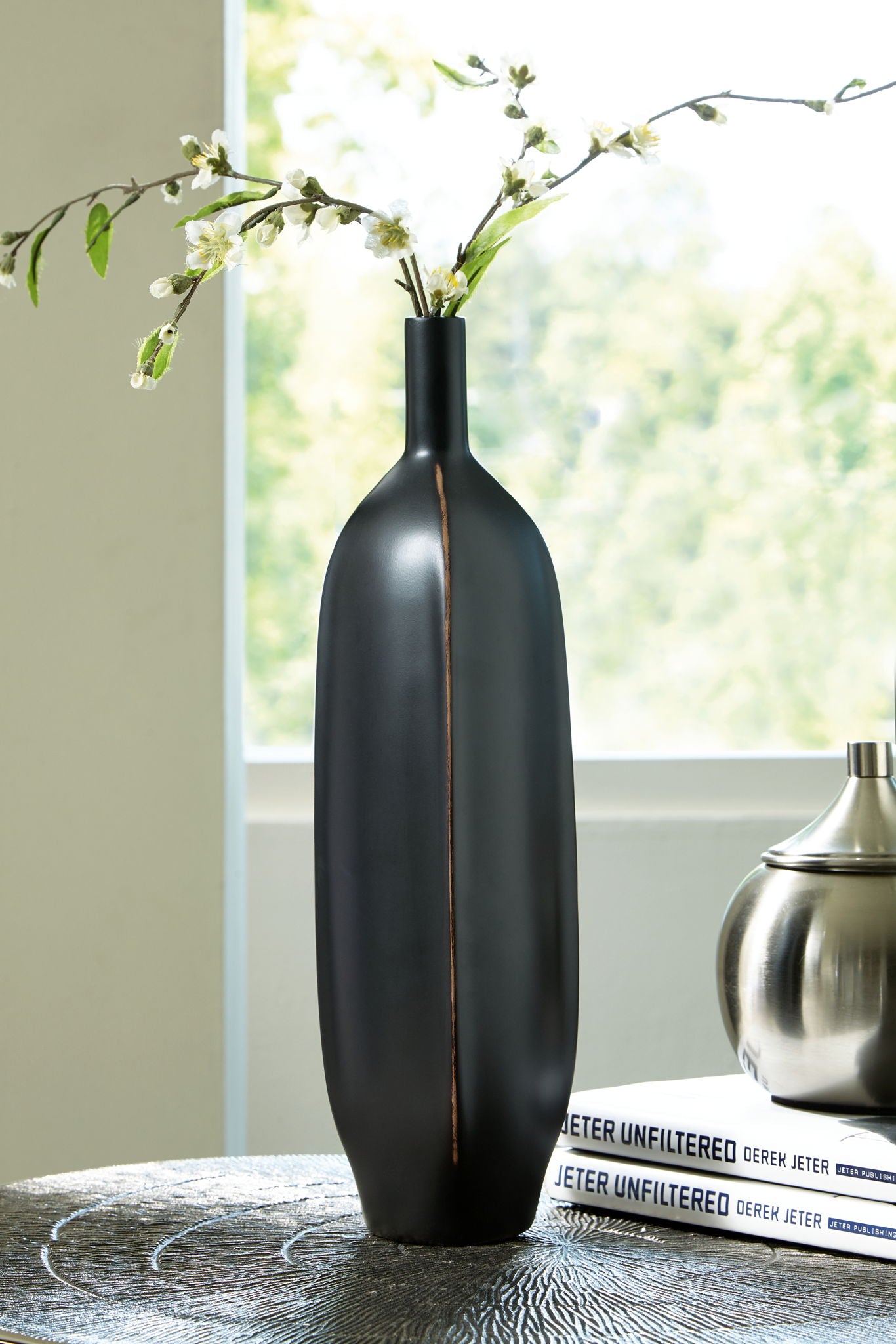 Rhaveney large black vase holding white flowers; vertical bronze stripe