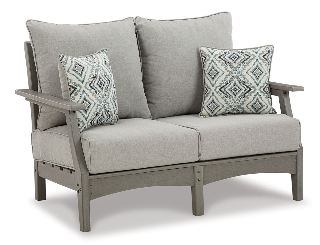 Gray outdoor loveseat with two accent pillows and thick padded armrests