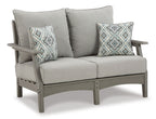 Gray outdoor loveseat with two accent pillows and thick padded armrests