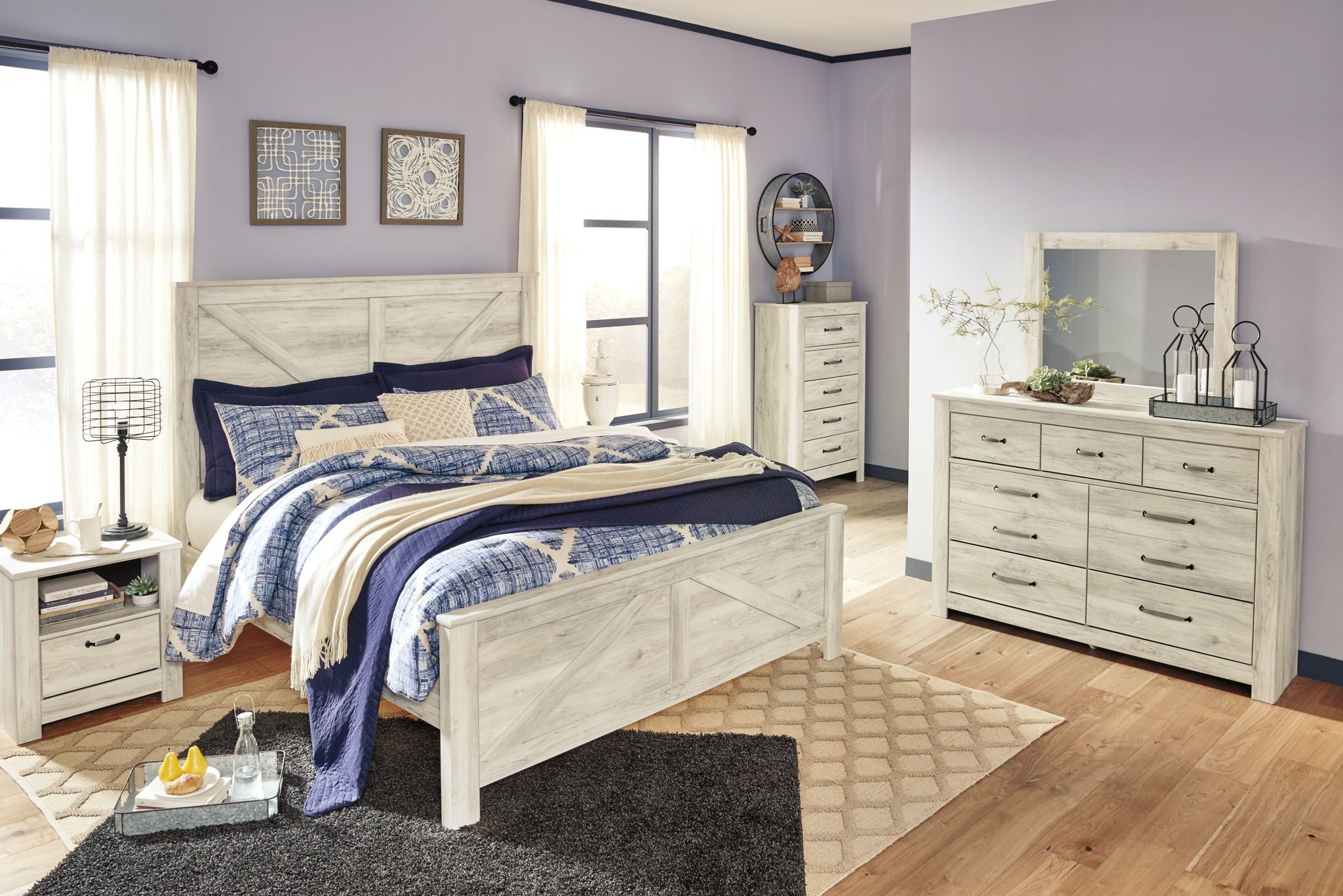 Beige crossbuck panel bed with blue-and-white bedding and dark accent pillows