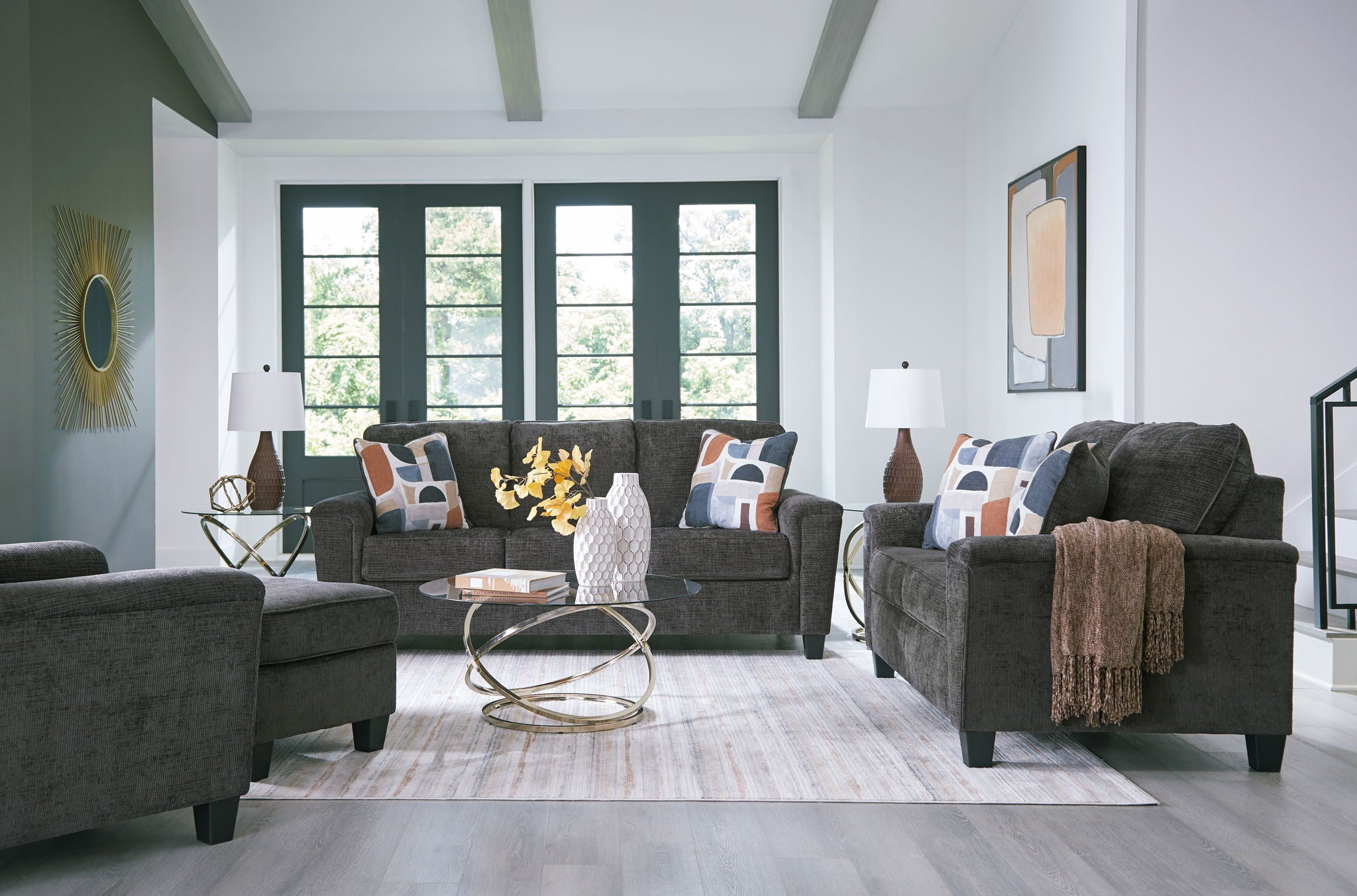 Black upholstered living room set with sofa, chairs, and patterned throw pillows