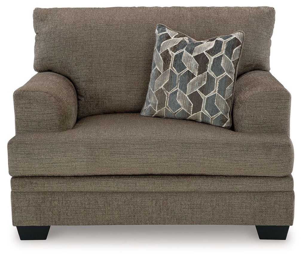 Brownish beige chair-and-a-half armchair with geometric throw pillow