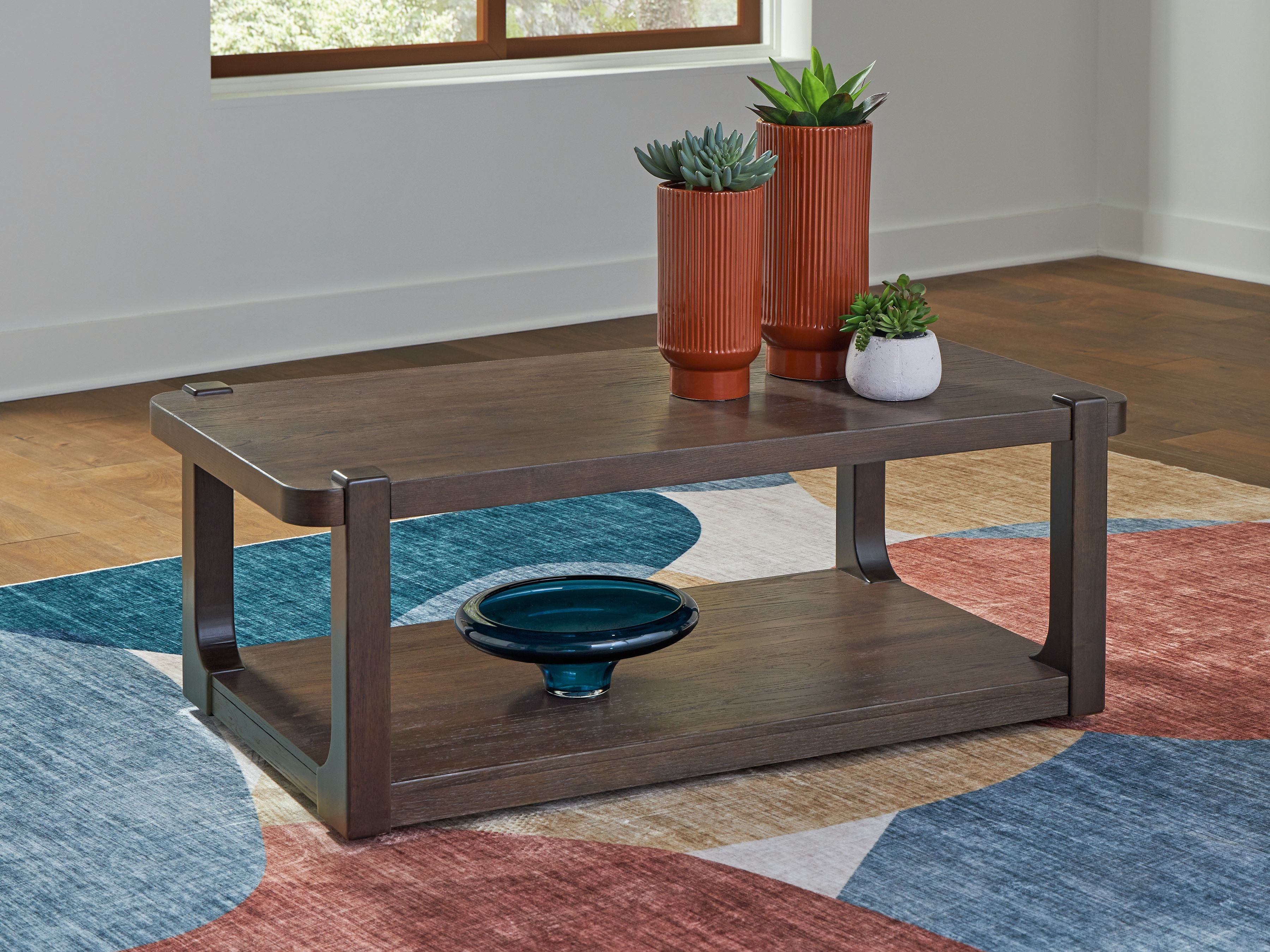 Dark brown two-tier table with open lower shelf and small items on top