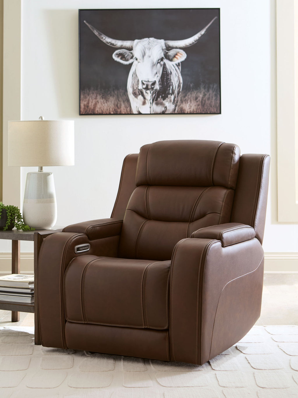 Brown power recliner with stitched back, cushioned arm pads, and reclined base