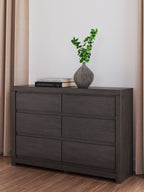 Charcoal six-drawer dresser with decor on top, including a small vase and books