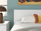 Wood panel bed headboard behind a white comforter and two accent pillows.