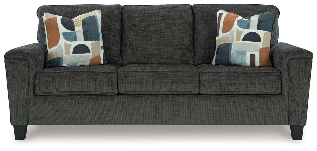 Black upholstered sofa with three seat cushions and four patterned throw pillows