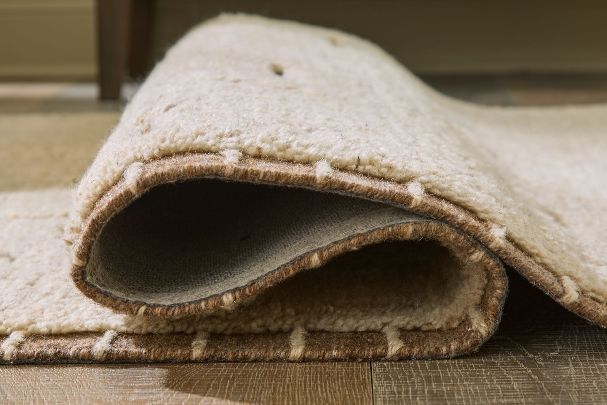 Beige rug edge with short pile and visible underside binding