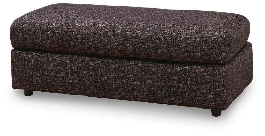 Oversized accent ottoman in dark woven fabric, cushioned seat, angled side view