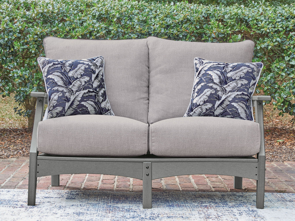 Gray loveseat with two blue palm-pattern throw pillows and padded seat cushions