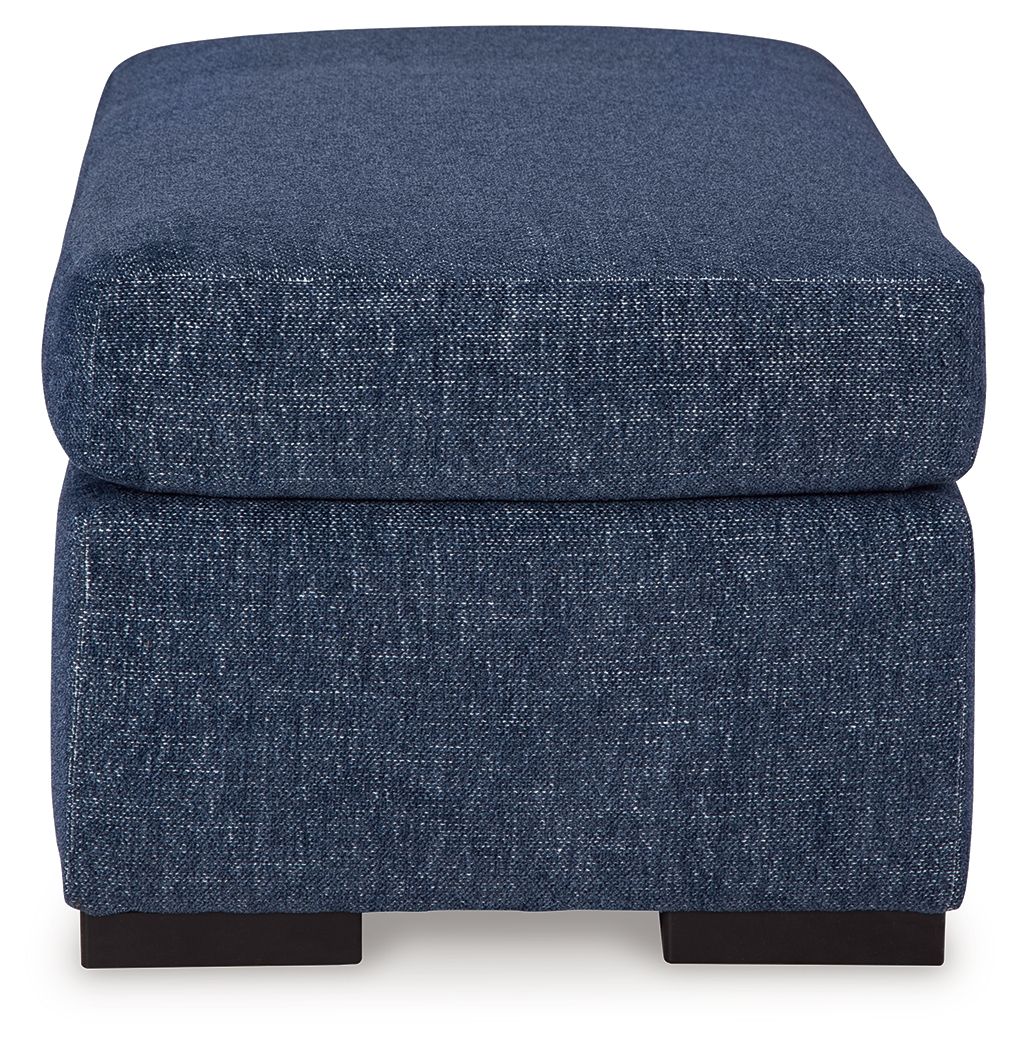 Blue upholstered ottoman with rounded cushioned top and dark legs