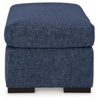 Blue upholstered ottoman with rounded cushioned top and dark legs