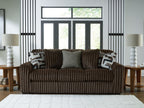 Dark brown corduroy sofa with two patterned throw pillows and a solid gray back cushion.
