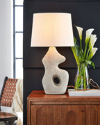 Paper table lamp with antique beige textured base and square fabric shade on sideboard