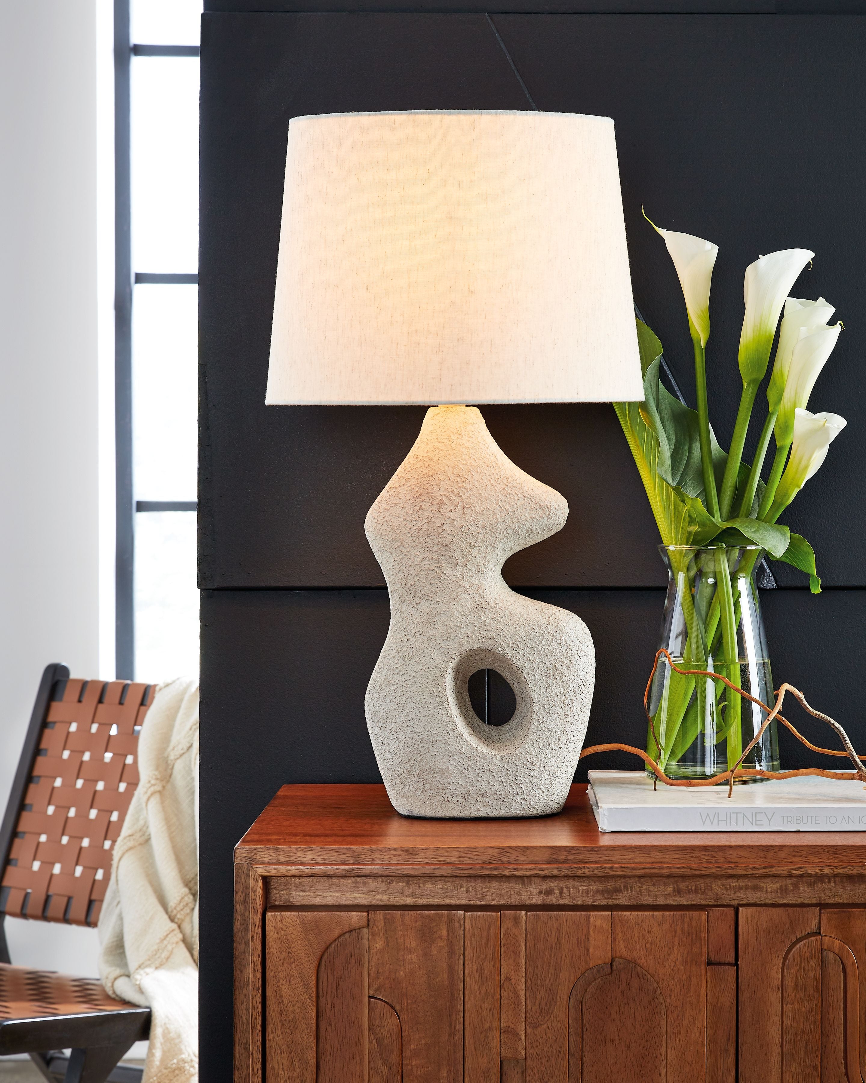 Paper table lamp with antique beige textured base and square fabric shade on sideboard