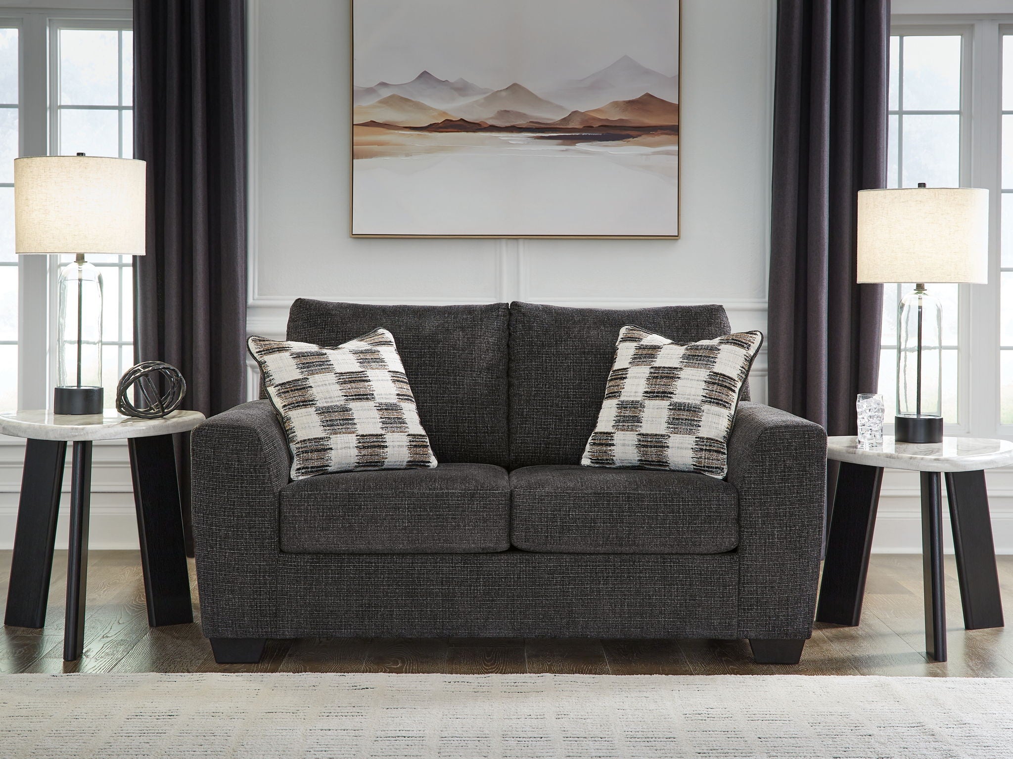 Dark gray loveseat with two plaid throw pillows