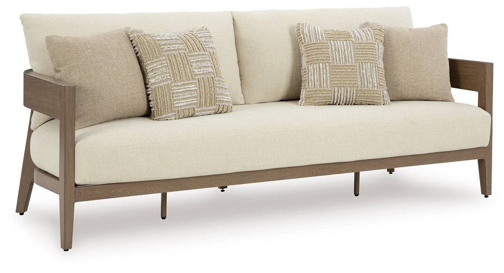 Outdoor lounge loveseat with beige seat and two patterned pillows, light-brown frame