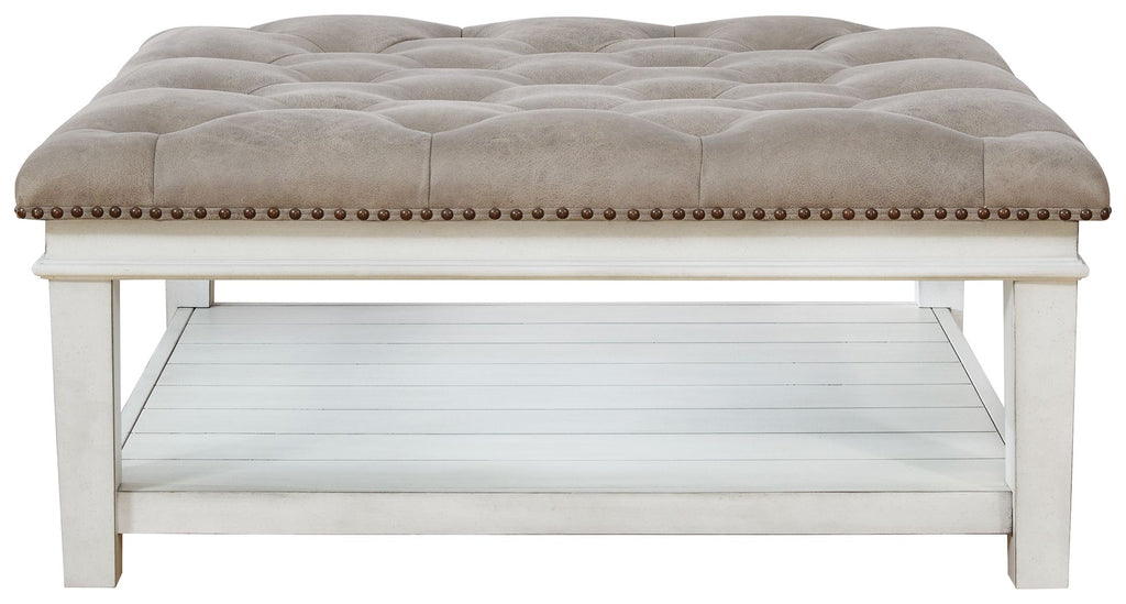 Tufted ottoman cocktail table with whitewash base, nailhead trim, open storage shelf