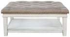 Tufted ottoman cocktail table with whitewash base, nailhead trim, open storage shelf