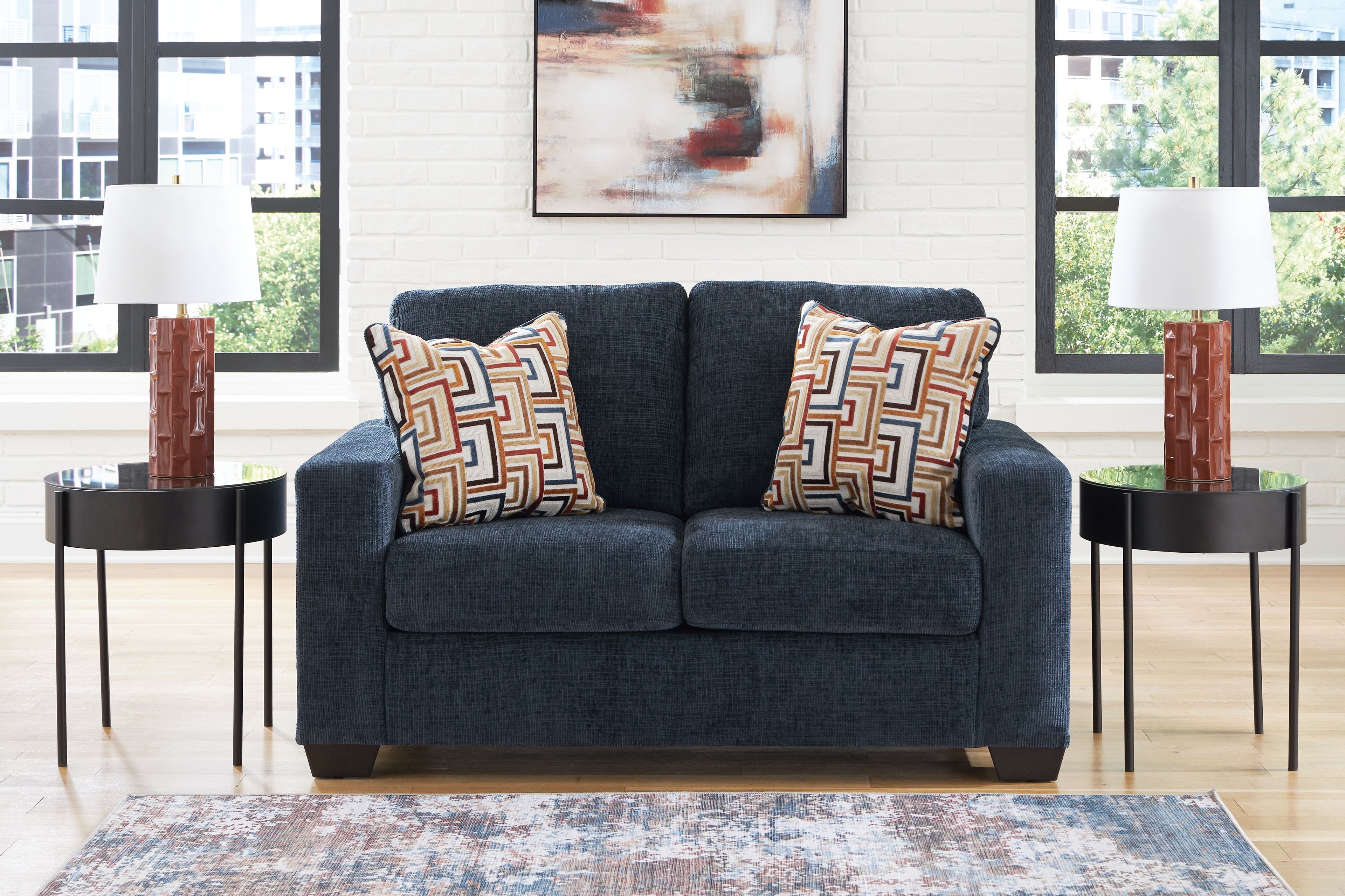 Dark navy loveseat with two patterned throw pillows and wide, cushioned arms.