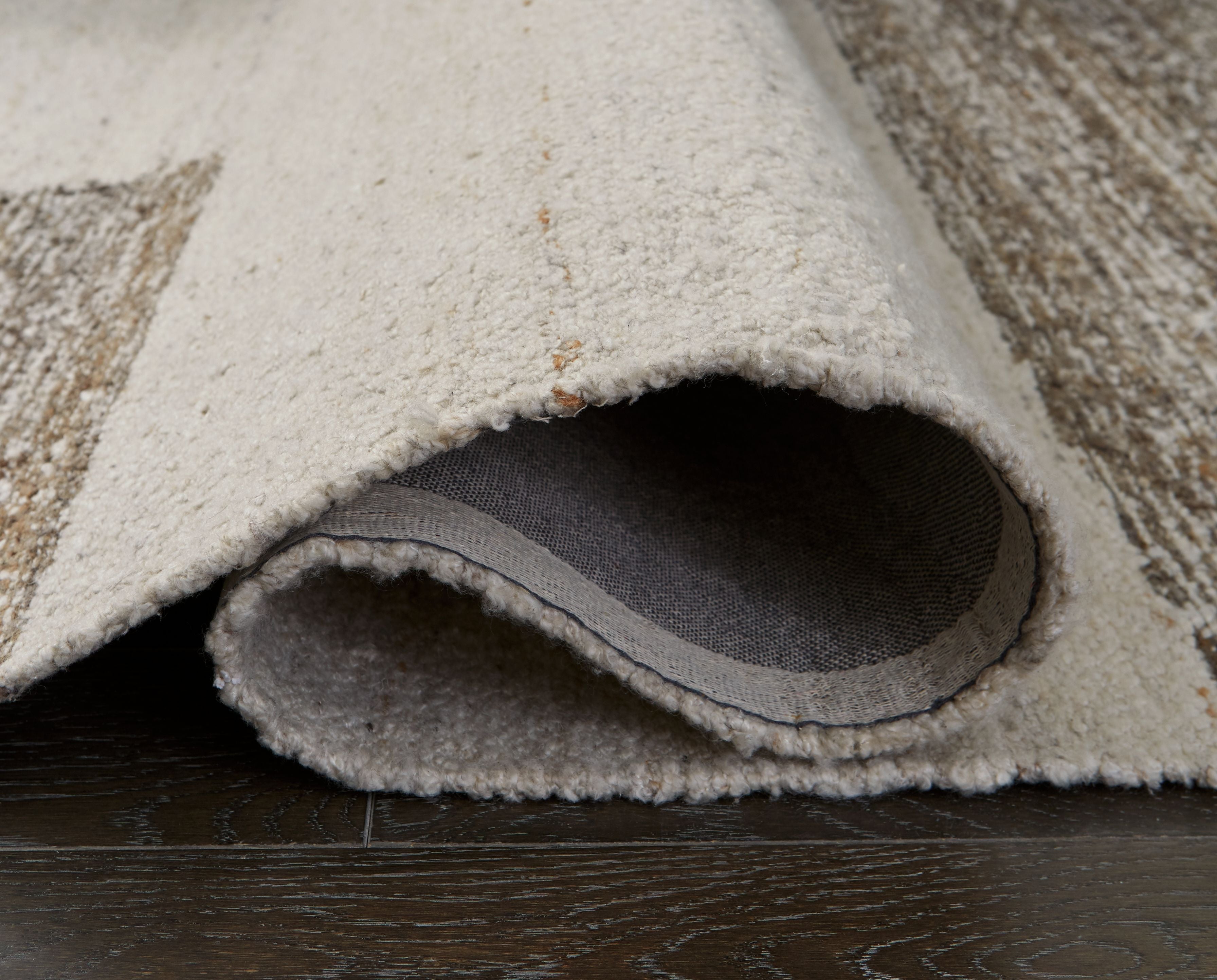 Barus rug with rolled edge showing gray backing and beige surface