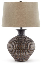 Antique bronze metal table lamp with textured urn base and beige fabric drum shade.