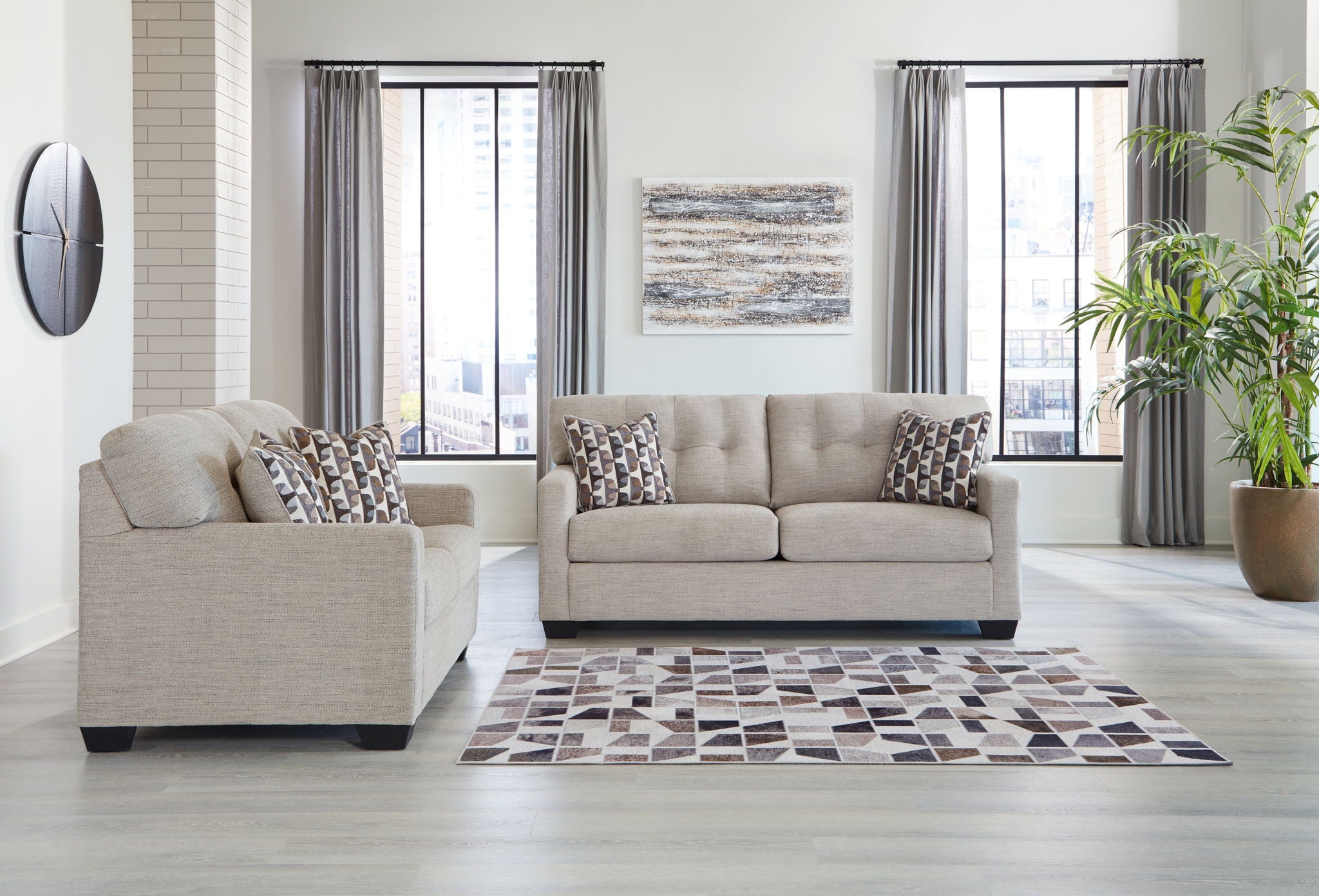 Light gray sofa set with matching loveseat and patterned throw pillows, dark feet
