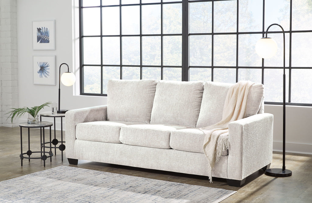 Light beige sofa with matching upholstered armrests and draped throws