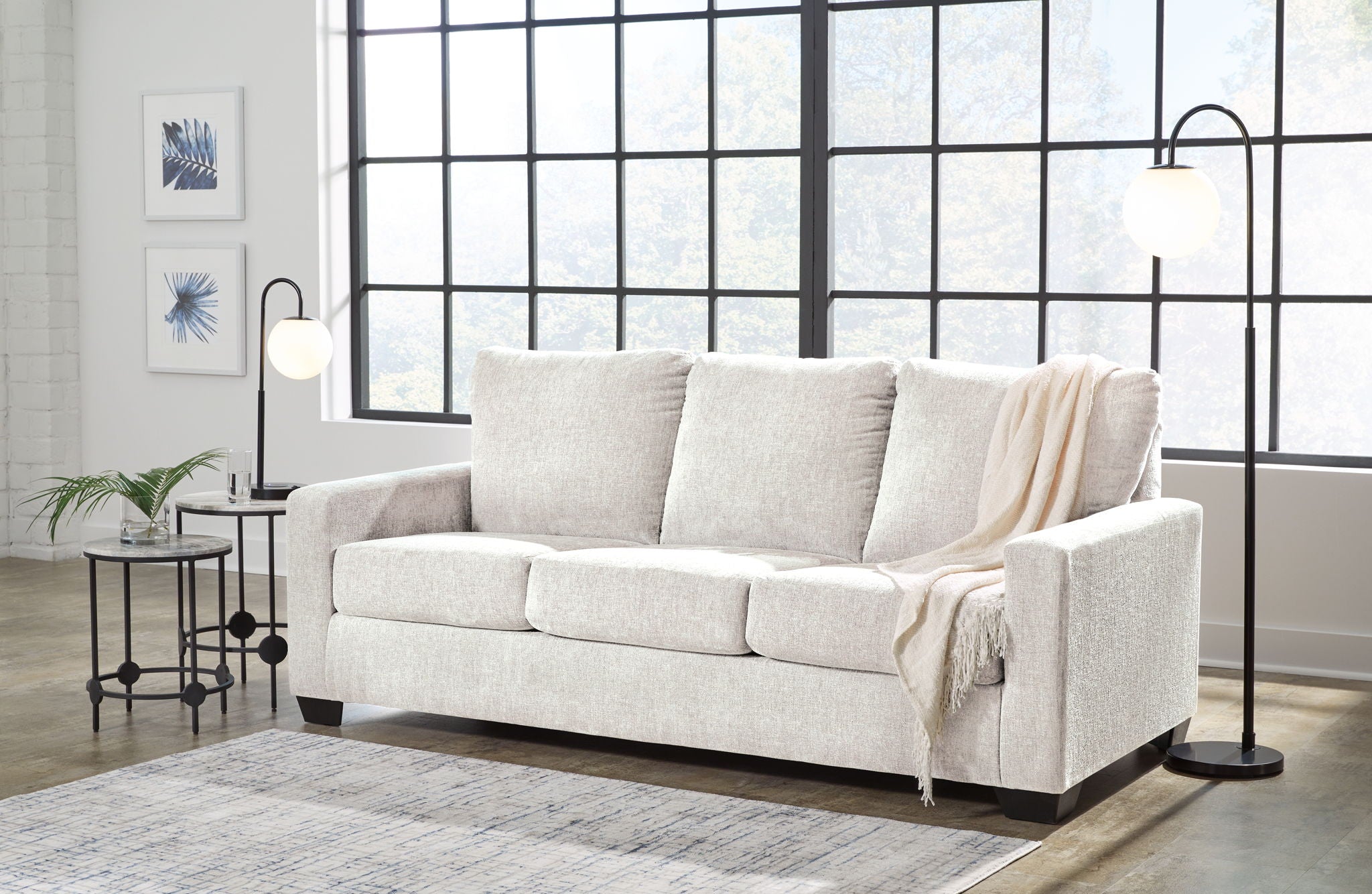 Light beige sofa with matching upholstered armrests and draped throws