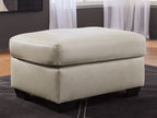 Light beige upholstered ottoman with cushioned top and dark block legs