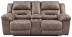 Reclining loveseat in taupe fabric with wide arm pads and central recline panel