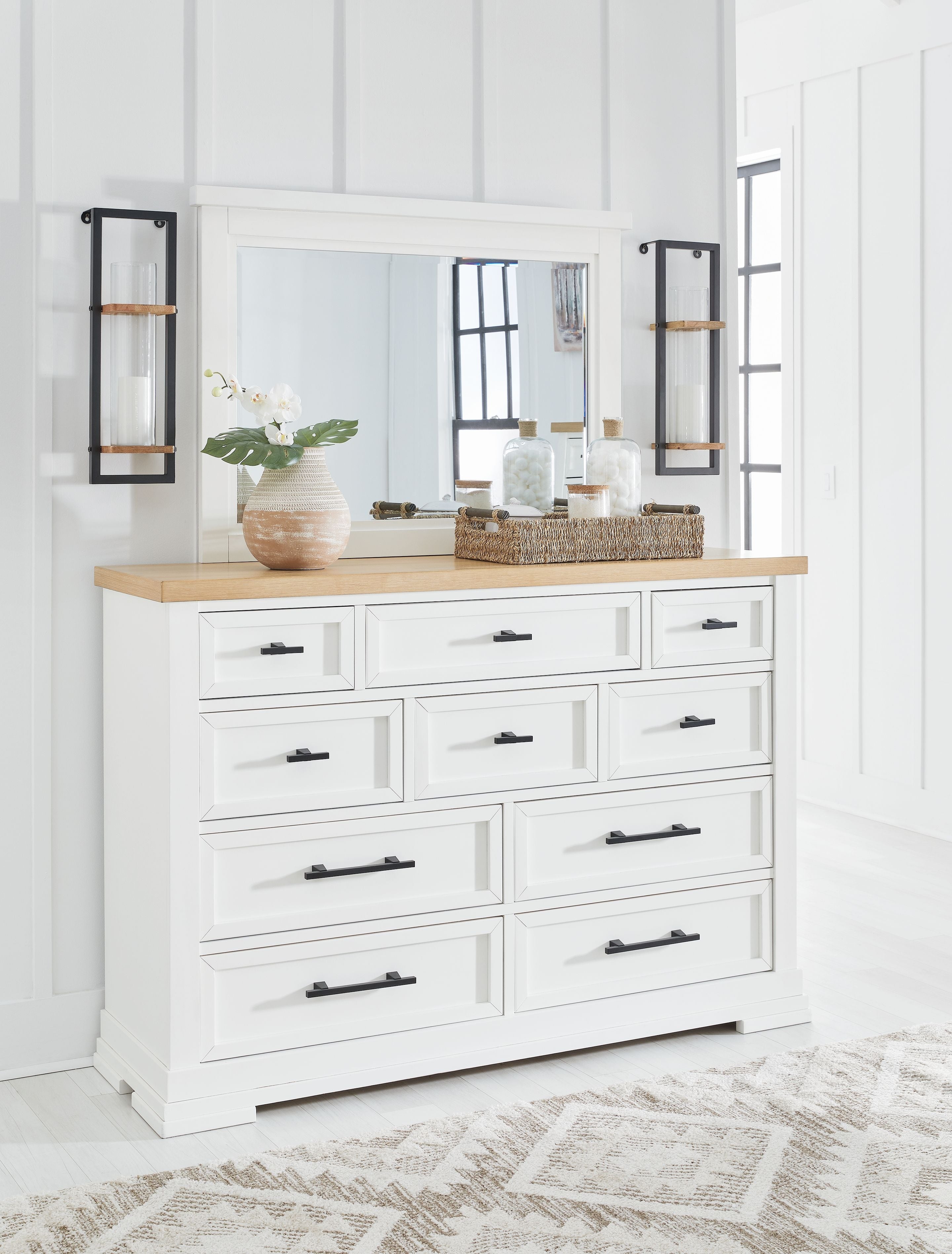 White dresser with mirror and light wood top, multiple drawers with black bar pulls