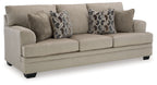 Light brown fabric sofa with two patterned accent pillows and square arms