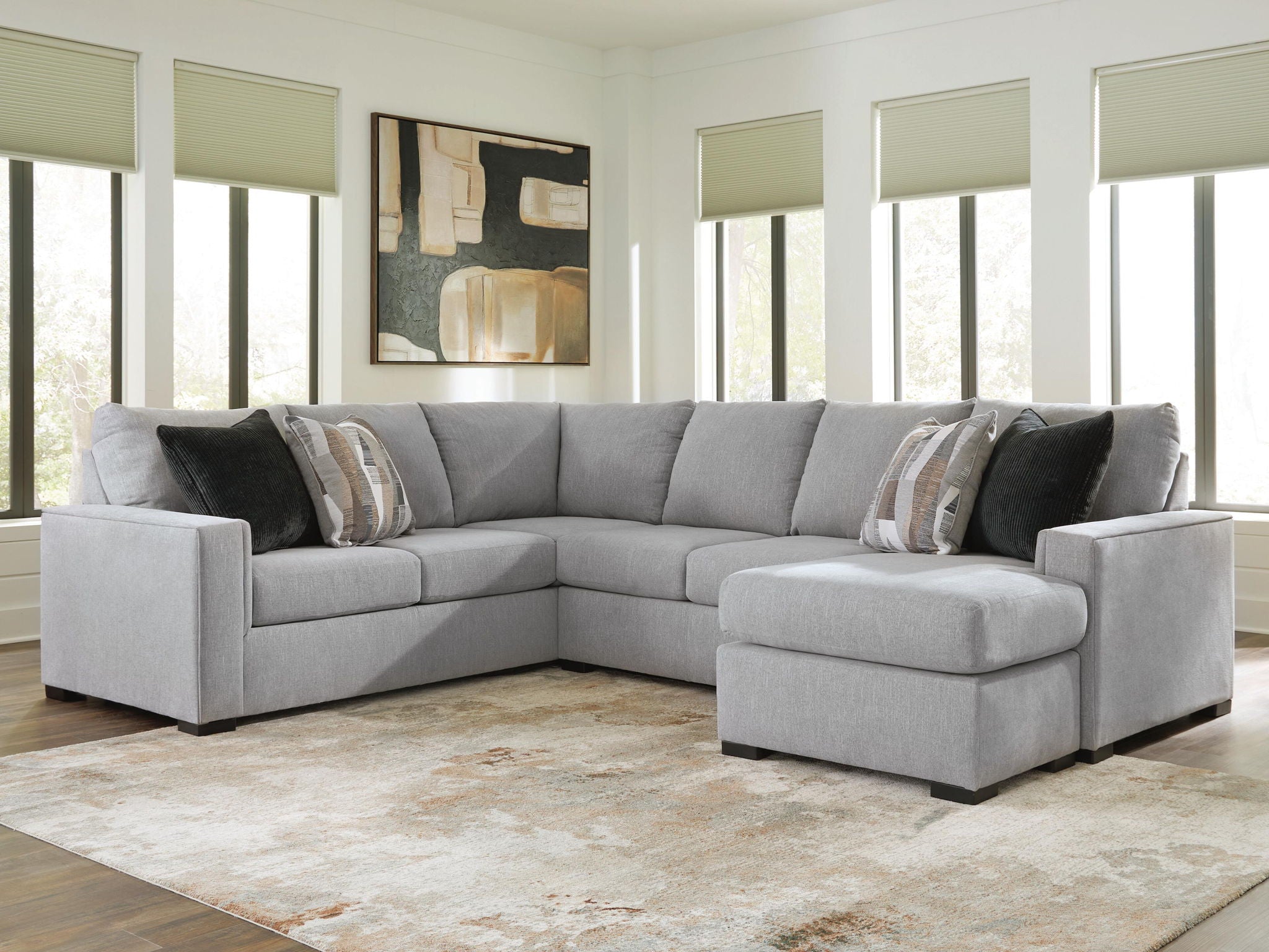 Light gray sectional sofa with chaise, cushioned ottoman, and throw pillows